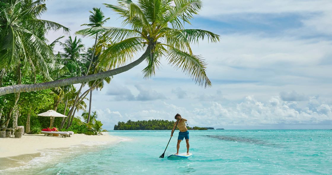 A Person Paddle Boarding On A Beach