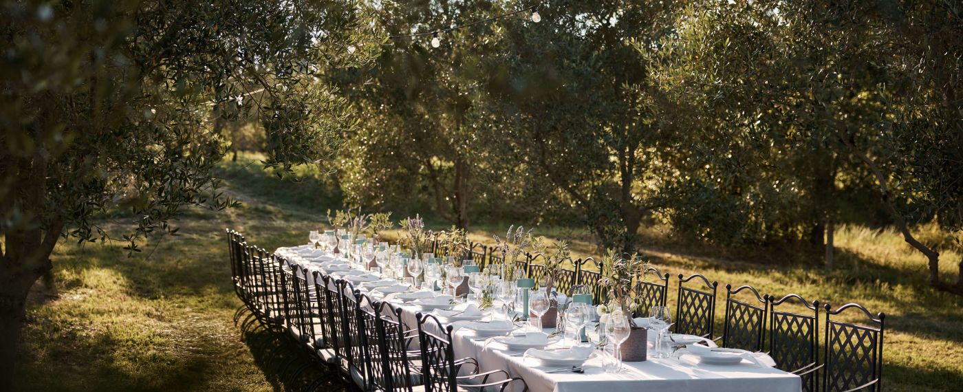 A Table Set With White Tables And Chairs In A Park