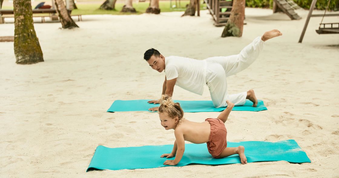 A Man And A Woman Doing Yoga On A Beach