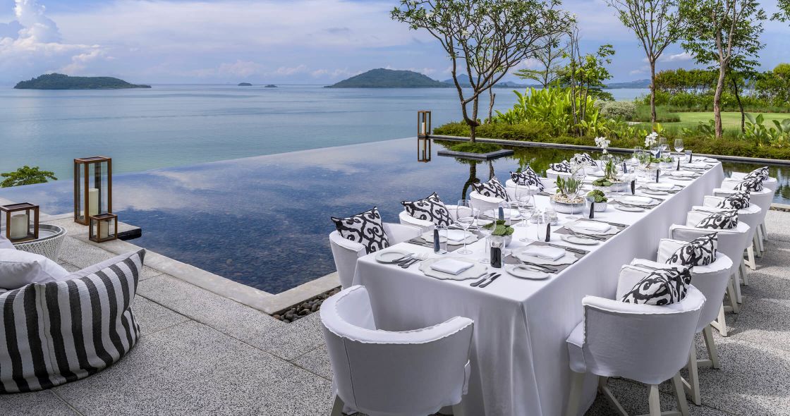 A Table Set With White Chairs And A View Of The Ocean