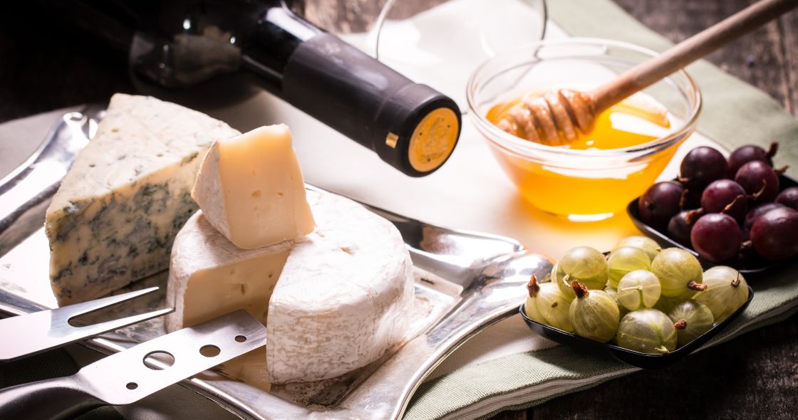 A Cutting Board With Cheese Grapes And A Knife