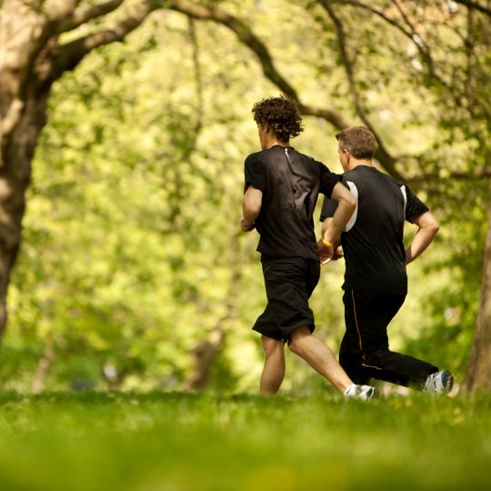 Two Men Running On A Grass Field