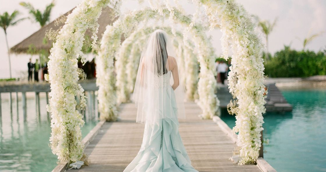 A Person In A Wedding Dress Standing On A Bridge Over Water