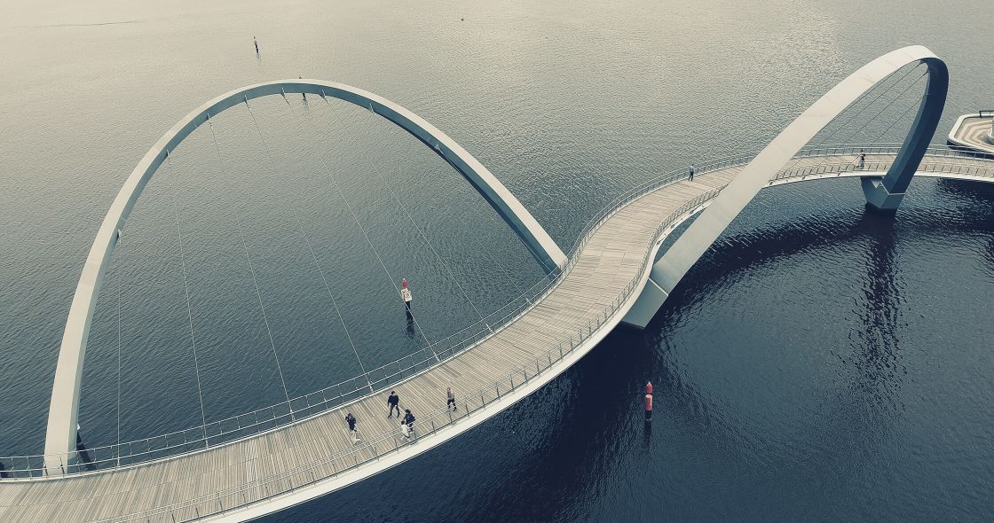 A Group Of People Walking On A Bridge
