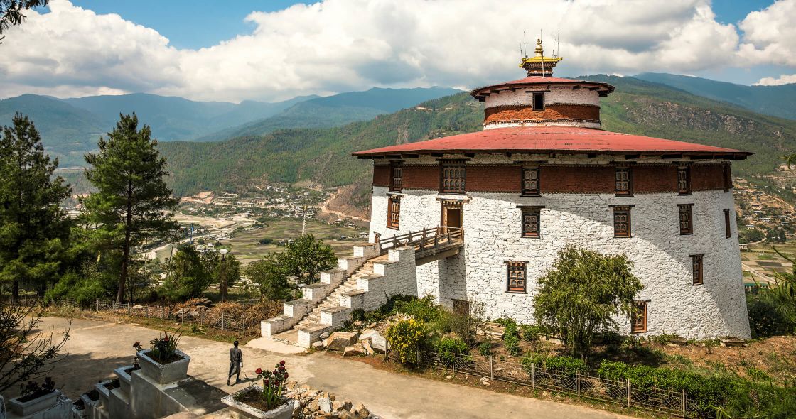 National Museum Of Bhutan With A Red Roof And A Red Roof With A Red Roof And Trees And Mountains In