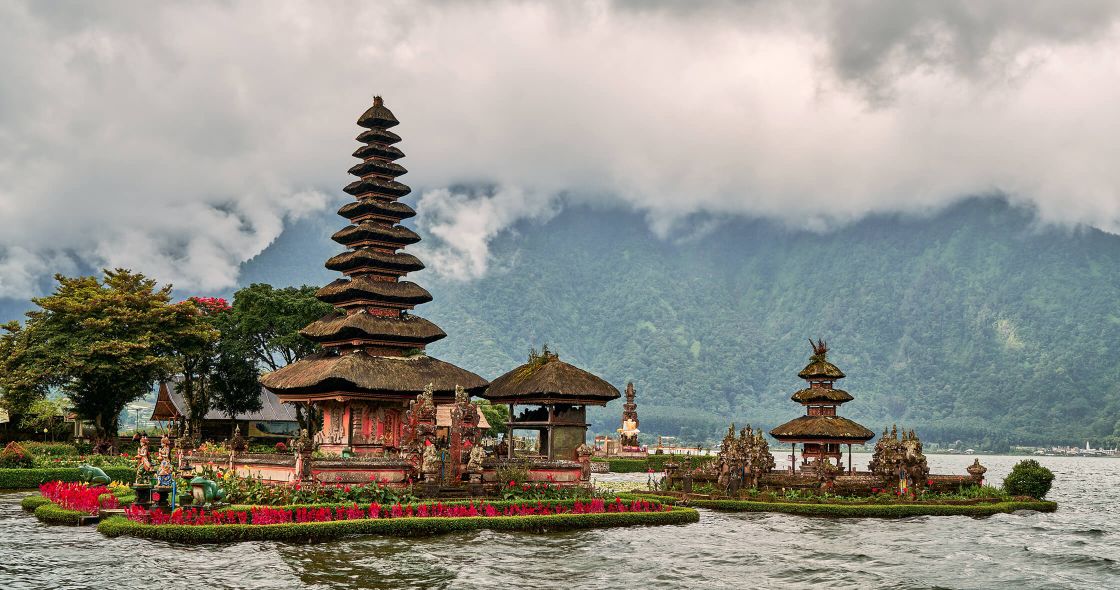 A Group Of Buildings Next To A Body Of Water With Bali In The Background