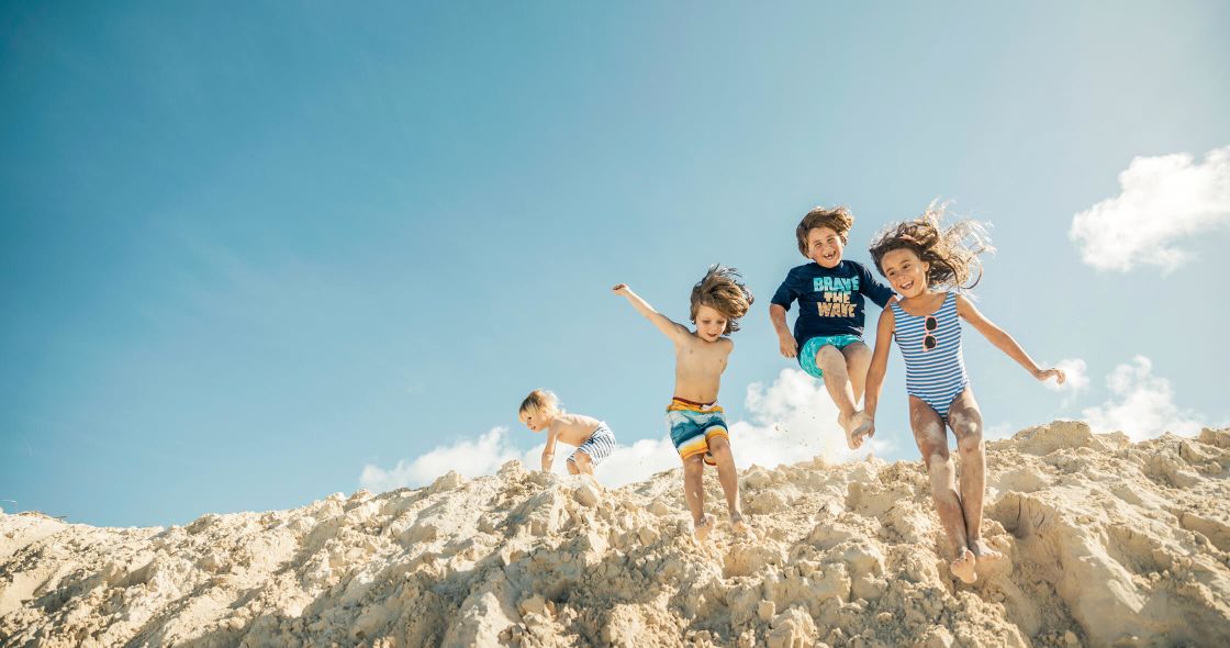 A Group Of Children Jumping On A Rocky Hill
