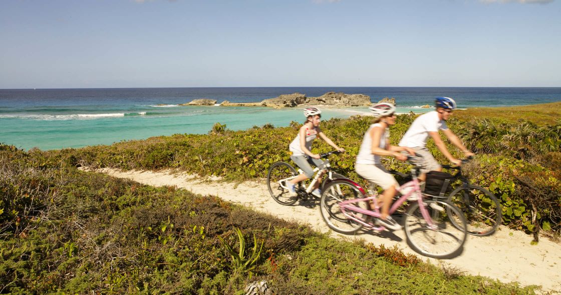 A Man And A Woman Riding Bikes On A Path By The Ocean