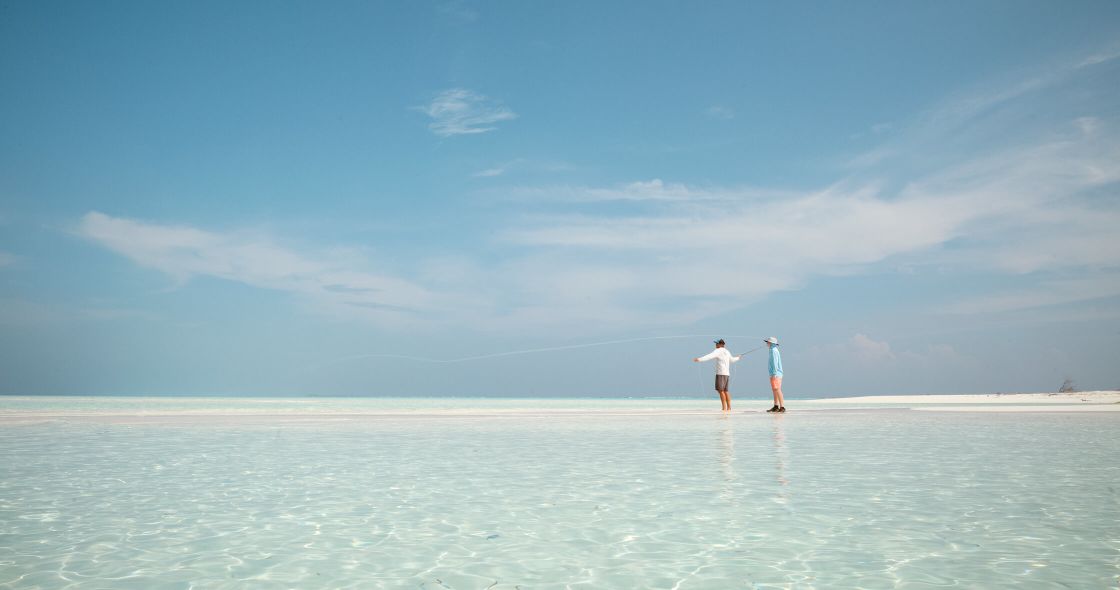 Two People Standing In A Large Body Of Water