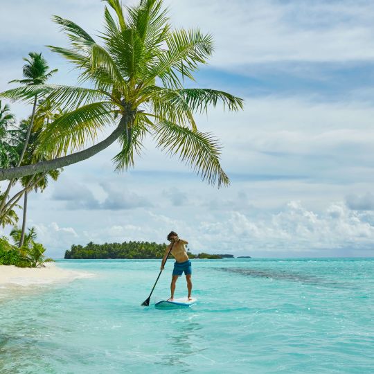 A Man Paddle Boarding In The Ocean