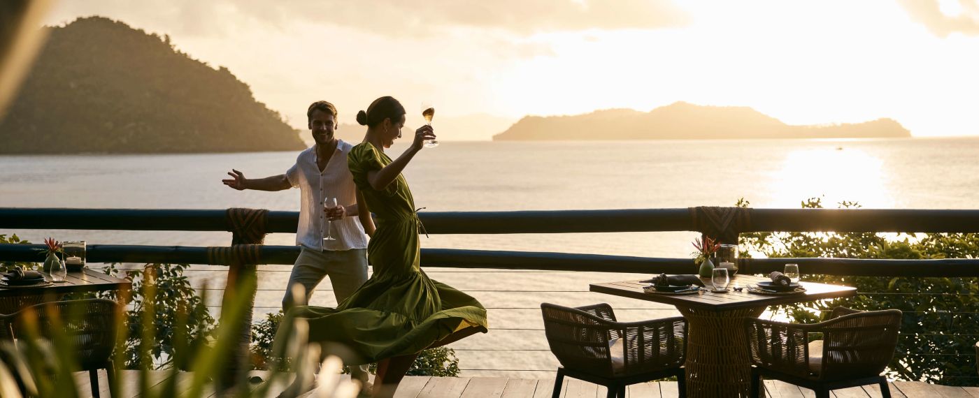 A Man And Woman Dancing On A Deck By The Water