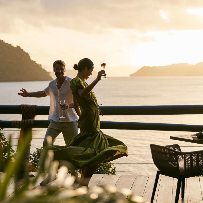 A Man And Woman Dancing On A Deck By The Water Image