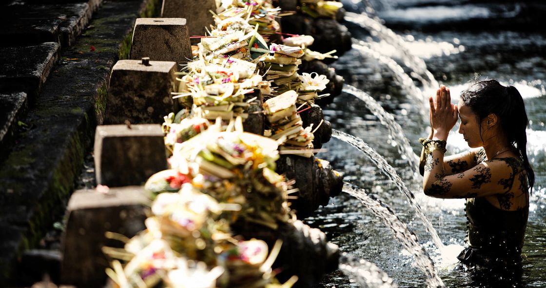 A Person Holding Flowers In Front Of A Waterfall
