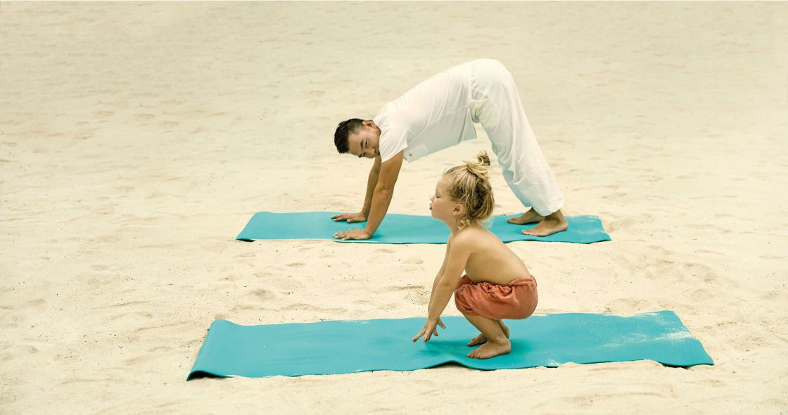 A Man And A Woman Doing Yoga On A Beach