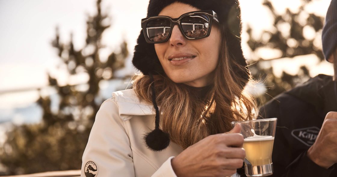 A Woman Wearing Sunglasses And Holding A Glass Of Beer