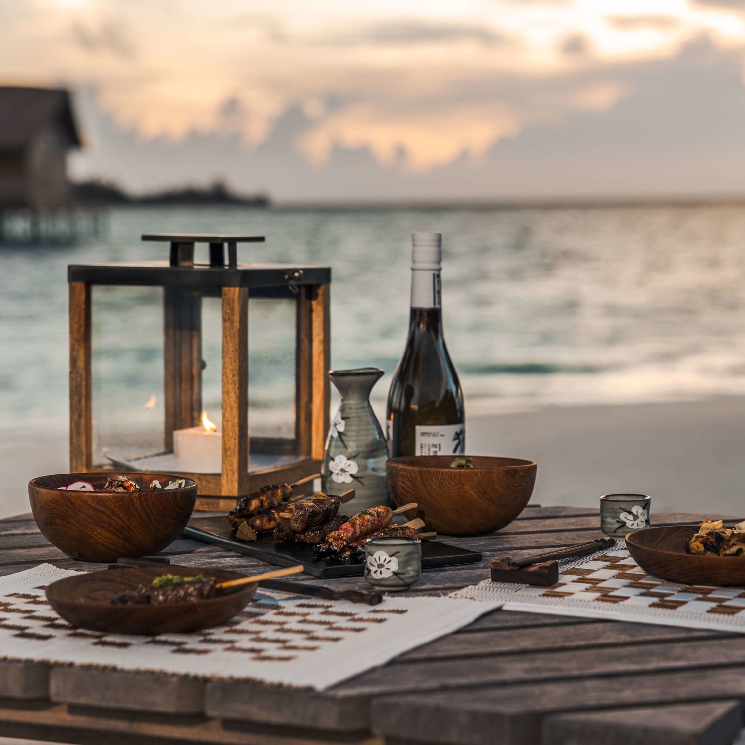 A Table With Food And Drinks On It By A Body Of Water