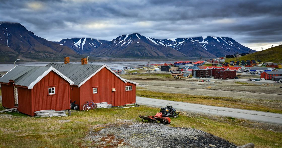 A Red Barn With A Motorcycle Parked In Front Of It With Lofoten In The Background
