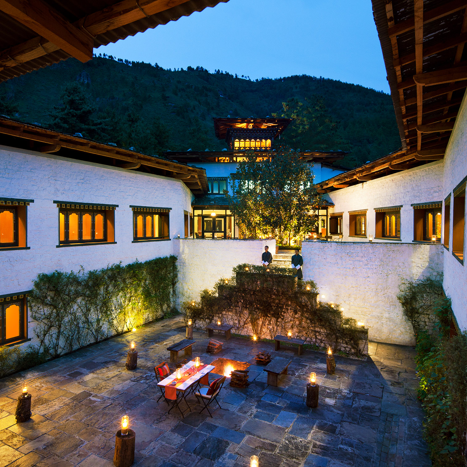 A Courtyard With A Building And A Mountain In The Background